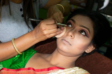 Hintli bir kadın gelin makyajı yaptırıyor.