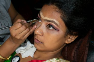 Hintli bir kadın gelin makyajı yaptırıyor.