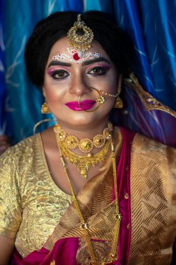 Gelin 'deki şirin bir Hint modelinin portresi. Ağır altın mücevher ve kırmızı sari ile.