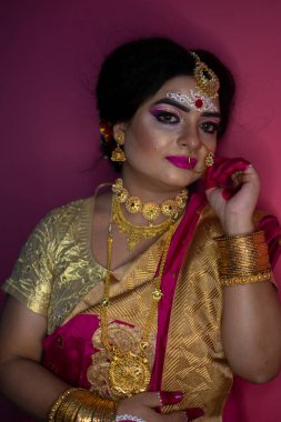 Geleneksel sari ve altın takılar takan Hintli kadının düğün portresi.