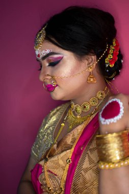 Geleneksel sari ve altın takılar takan Hintli kadının düğün portresi.