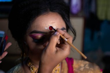 Hindistan 'da bir gelinin alnına Kolka ya da Bindi adında güzel bir tasarım çizen bir makyöz.