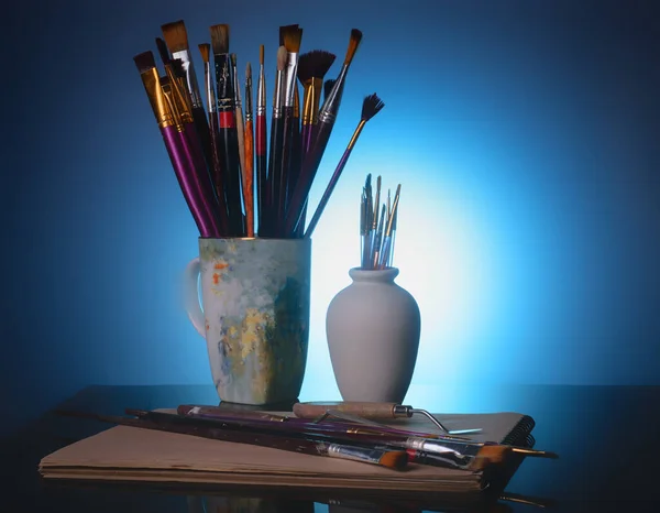 tools of the artist - brushes and palette knife on a  blue background