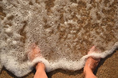 Sahilde duran köpüklü kadın bacaklarını kapat.