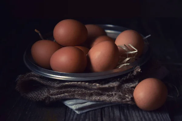 clean eggs in a metal bowl on a dark background. . Dark and moody picture. Low key. Rustic.  Close up, selective focus.