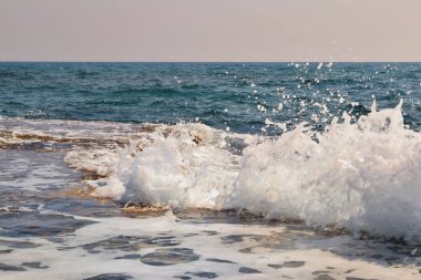 Kayalık bir kıyıda büyük bir dalga akıyor.