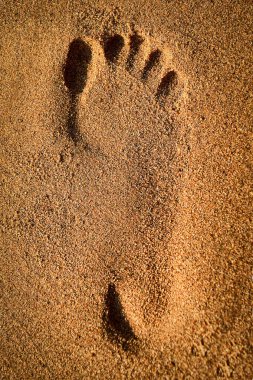 Sahildeki sarı kumda tek ayak izi dinlenme ya da tatilin sembolü.