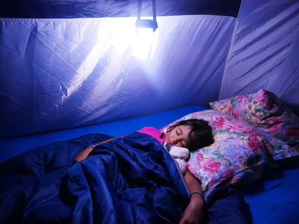 Menina Metis dormindo profundamente em uma barraca de acampamento durante as férias. Imagem De Stock