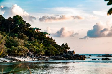 Tayland 'ın Koh Phangan adasındaki yemyeşil tropikal bitki örtüsü arasında bir yamaçtaki turistler için bungalovlar.