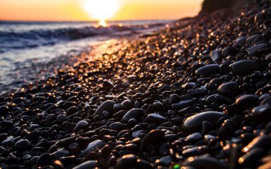 Rusya 'nın Anapa eyaletinin Bolshoy Utrish köyü yakınlarındaki bir çakıl taşı kıyısına güzel bir günbatımı yansıtılır.