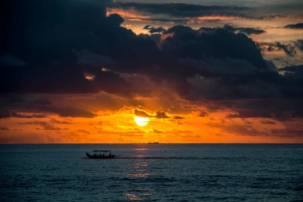 Boat in the ocean against the backdrop of a beautiful sunset and cloudy sky near Bali, Indonesia