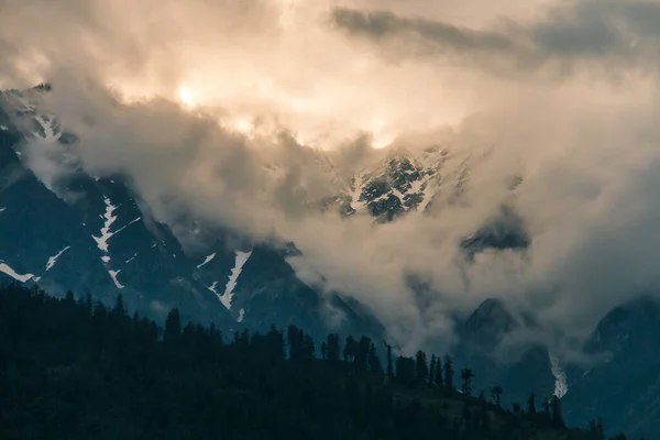 Himalaya dağlarının ormanlı ve karlı zirveleri Manali, Himachal Pradesh, Hindistan yakınlarındaki gri bulutlarda.