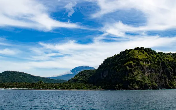 Endonezya 'daki Gili adasından gelen bulutlarla mavi gökyüzüne karşı Agun volkanı ve dağların manzarası