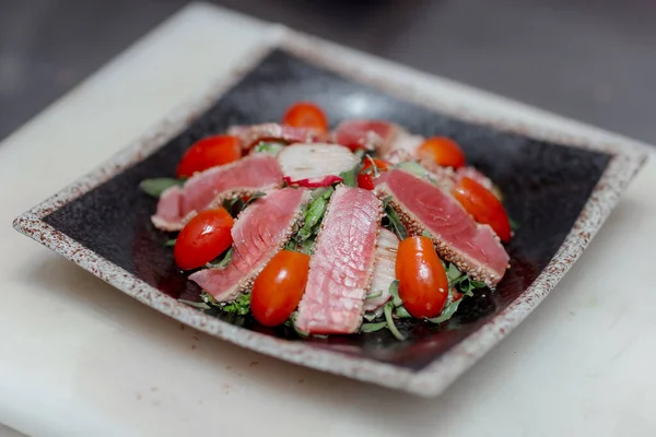 Restoran balık parçalarının üzerine susam, domates ve bitki serpiştirilmiş beyaz bir tahtanın üzerinde hazır yapılmış sağlıklı bir tabağın güzel üst görüntüsü.