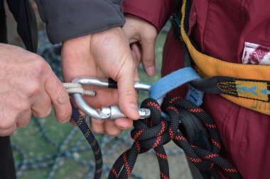 Yakın dağcı eller yukarıda alpinist, ayarlama tırmanma dişli, Emanet ipleri hazırlanıyor.