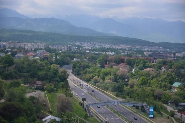 Panoraamanäkymät Almatyn kaupunkiin, jossa on tie, teollisuusalue, vuoret ja taivas pilvillä. Katse paikasta Kok tobe, Kazakstan . — kuvapankkivalokuva