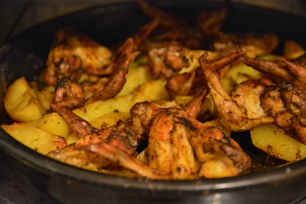 Patatas fritas al horno con deliciosas alas de pollo fritas con corteza dorada servidas con salsas en tazón negro sobre fondo de mesa de madera. Enfoque selectivo . — Foto de Stock