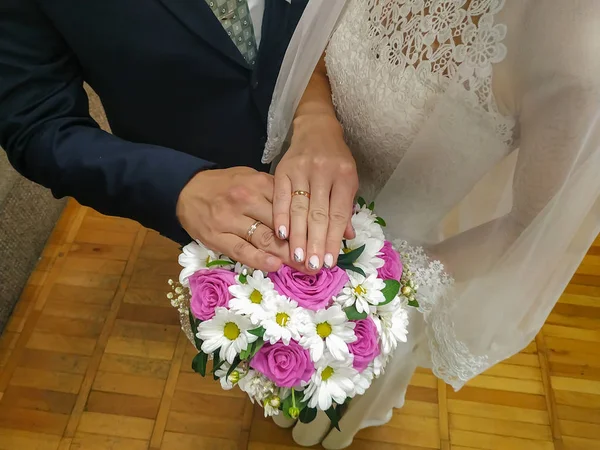结婚戒指和两只手一起放在一个粉红色的花束上. — 图库照片
