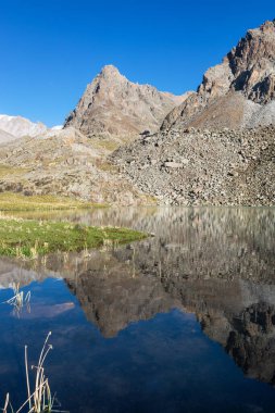 Dağlarda güzel yeşil dağ çayırları, yansımalı göl ve bulutlarla donuk bir yaz manzarası. Kırgız Alatoo Dağları, Tian-Shan, Ala-archa, Kırgızistan.