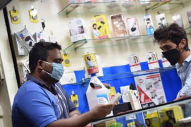 Hyderabad, Telangana, Hindistan. Haziran-29-2020: Mobile Shop 'ta iki kişi arasında yapılan görüşme, Corona virüsü, hava kirliliği ve sağlık konseptine karşı tıbbi maske takıyor