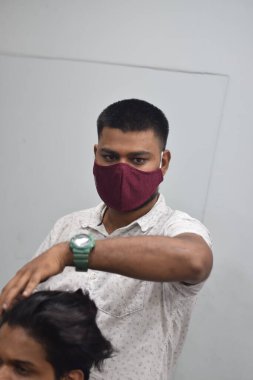Hyderabad, Telangana, Hindistan. Haziran-29-2020: Koruyucu yüz maskesi takan bir kuaför, bir berber dükkanında çalışıyor. Kapandıktan sonra covid-19 için yeniden aç.