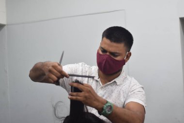 Hyderabad, Telangana, Hindistan. Haziran-29-2020: Koruyucu yüz maskesi takan bir kuaför, bir berber dükkanında çalışıyor. Kapandıktan sonra covid-19 için yeniden aç.