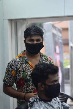 Hyderabad, Telangana, Hindistan. Haziran-29-2020: Koruyucu yüz maskesi takan bir kuaför, bir berber dükkanında çalışıyor. Kapandıktan sonra covid-19 için yeniden aç.