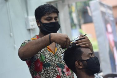 Hyderabad, Telangana, Hindistan. Haziran-29-2020: Koruyucu yüz maskesi takan bir kuaför, bir berber dükkanında çalışıyor. Kapandıktan sonra covid-19 için yeniden aç.