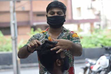 Hyderabad, Telangana, Hindistan. Haziran-29-2020: Koruyucu yüz maskesi takan bir kuaför, bir berber dükkanında çalışıyor. Kapandıktan sonra covid-19 için yeniden aç.