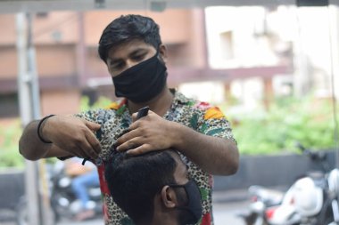 Hyderabad, Telangana, Hindistan. Haziran-29-2020: Koruyucu yüz maskesi takan bir kuaför, bir berber dükkanında çalışıyor. Kapandıktan sonra covid-19 için yeniden aç.