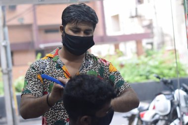 Hyderabad, Telangana, Hindistan. Haziran-29-2020: Koruyucu yüz maskesi takan bir kuaför, bir berber dükkanında çalışıyor. Kapandıktan sonra covid-19 için yeniden aç.