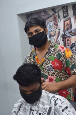 Hyderabad, Telangana, Hindistan. Haziran-29-2020: Koruyucu yüz maskesi takan bir kuaför, bir berber dükkanında çalışıyor. Kapandıktan sonra covid-19 için yeniden aç.
