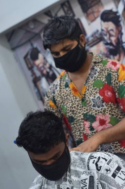 Hyderabad, Telangana, Hindistan. Haziran-29-2020: Koruyucu yüz maskesi takan bir kuaför, bir berber dükkanında çalışıyor. Kapandıktan sonra covid-19 için yeniden aç.