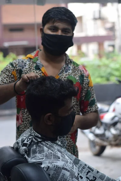 Hyderabad, Telangana, Hindistan. Haziran-29-2020: Koruyucu yüz maskesi takan bir kuaför, bir berber dükkanında çalışıyor. Kapandıktan sonra covid-19 için yeniden aç.