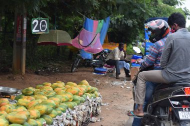 Hyderabad, Telangana, Hindistan. Temmuz-22-2020: Meyveler yol kenarında, meyve tüccarı yol kenarında meyve satarken koronavirüsten korunmak için maske takıyor, korona salgını zamanı, insanlar meyve alırken koruyucu maskeler takıyor