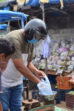 Hyderabad, Telangana, Hindistan. Temmuz-22-2020: Meyveler yol kenarında, meyve tüccarı yol kenarında meyve satarken koronavirüsten korunmak için maske takıyor, korona salgını zamanı, insanlar meyve alırken koruyucu maskeler takıyor