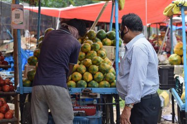 Hyderabad, Telangana, Hindistan. Temmuz-22-2020: Meyveler yol kenarında, meyve tüccarı yol kenarında meyve satarken koronavirüsten korunmak için maske takıyor, korona salgını zamanı, insanlar meyve alırken koruyucu maskeler takıyor