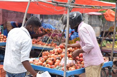 Hyderabad, Telangana, Hindistan. Temmuz-22-2020: Meyveler yol kenarında, meyve tüccarı yol kenarında meyve satarken koronavirüsten korunmak için maske takıyor, korona salgını zamanı, insanlar meyve alırken koruyucu maskeler takıyor