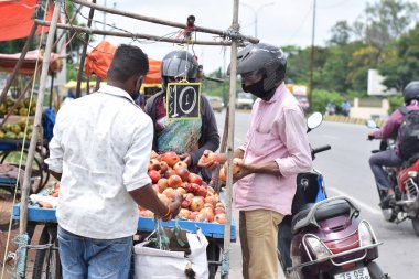 Hyderabad, Telangana, Hindistan. Temmuz-22-2020: Meyveler yol kenarında, meyve tüccarı yol kenarında meyve satarken koronavirüsten korunmak için maske takıyor, korona salgını zamanı, insanlar meyve alırken koruyucu maskeler takıyor