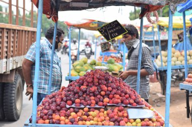 Hyderabad, Telangana, Hindistan. Temmuz-22-2020: Meyveler yol kenarında, meyve tüccarı yol kenarında meyve satarken koronavirüsten korunmak için maske takıyor, korona salgını zamanı, insanlar meyve alırken koruyucu maskeler takıyor