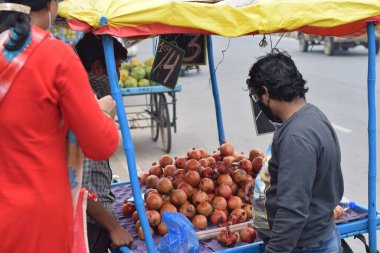 Hyderabad, Telangana, Hindistan. Temmuz-22-2020: Meyveler yol kenarında, meyve tüccarı yol kenarında meyve satarken koronavirüsten korunmak için maske takıyor, korona salgını zamanı, insanlar meyve alırken koruyucu maskeler takıyor