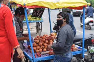 Hyderabad, Telangana, Hindistan. Temmuz-22-2020: Meyveler yol kenarında, meyve tüccarı yol kenarında meyve satarken koronavirüsten korunmak için maske takıyor, korona salgını zamanı, insanlar meyve alırken koruyucu maskeler takıyor