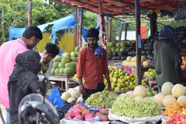 Hyderabad, Telangana, Hindistan. Temmuz-22-2020: Meyveler yol kenarında, meyve tüccarı yol kenarında meyve satarken koronavirüsten korunmak için maske takıyor, korona salgını zamanı, insanlar meyve alırken koruyucu maskeler takıyor