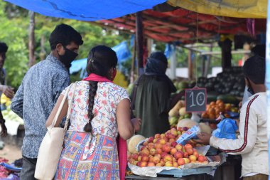 Hyderabad, Telangana, Hindistan. Temmuz-22-2020: Meyveler yol kenarında, meyve tüccarı yol kenarında meyve satarken koronavirüsten korunmak için maske takıyor, korona salgını zamanı, insanlar meyve alırken koruyucu maskeler takıyor
