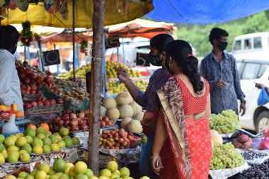 Hyderabad, Telangana, Hindistan. Temmuz-22-2020: Meyveler yol kenarında, meyve tüccarı yol kenarında meyve satarken koronavirüsten korunmak için maske takıyor, korona salgını zamanı, insanlar meyve alırken koruyucu maskeler takıyor