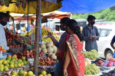 Hyderabad, Telangana, Hindistan. Temmuz-22-2020: Meyveler yol kenarında, meyve tüccarı yol kenarında meyve satarken koronavirüsten korunmak için maske takıyor, korona salgını zamanı, insanlar meyve alırken koruyucu maskeler takıyor