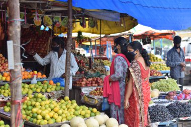 Hyderabad, Telangana, Hindistan. Temmuz-22-2020: Meyveler yol kenarında, meyve tüccarı yol kenarında meyve satarken koronavirüsten korunmak için maske takıyor, korona salgını zamanı, insanlar meyve alırken koruyucu maskeler takıyor