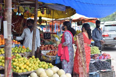 Hyderabad, Telangana, Hindistan. Temmuz-22-2020: Meyveler yol kenarında, meyve tüccarı yol kenarında meyve satarken koronavirüsten korunmak için maske takıyor, korona salgını zamanı, insanlar meyve alırken koruyucu maskeler takıyor