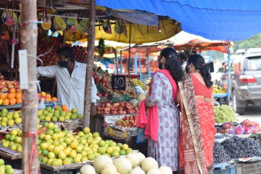 Hyderabad, Telangana, Hindistan. Temmuz-22-2020: Meyveler yol kenarında, meyve tüccarı yol kenarında meyve satarken koronavirüsten korunmak için maske takıyor, korona salgını zamanı, insanlar meyve alırken koruyucu maskeler takıyor