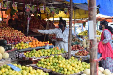 Hyderabad, Telangana, Hindistan. Temmuz-22-2020: Meyveler yol kenarında, meyve tüccarı yol kenarında meyve satarken koronavirüsten korunmak için maske takıyor, korona salgını zamanı, insanlar meyve alırken koruyucu maskeler takıyor